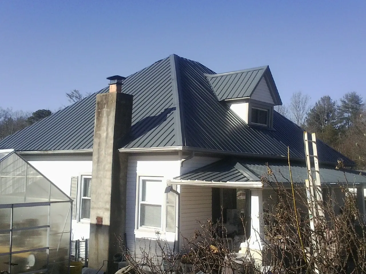 Dark blue standing seam metal roof on a white farmhouse with dormer — Slate & Tile Roof Repair by Roofing Brothers in Hillsboro